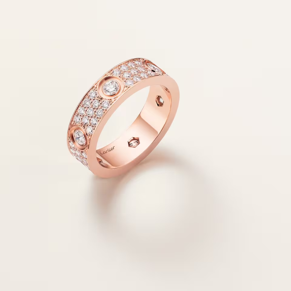 Rose gold ring with diamond accents on a light pink background