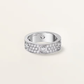 Silver ring with embedded diamonds on a light gray background