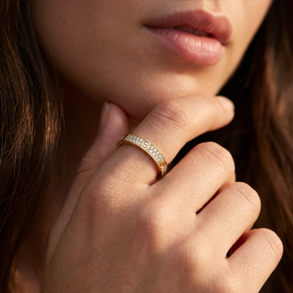 Close-up of a hand wearing a gold ring with small diamonds, touching the chin.