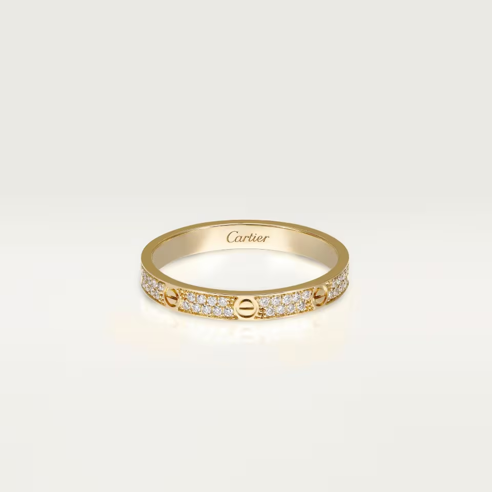 Gold ring with diamond accents on a light beige background