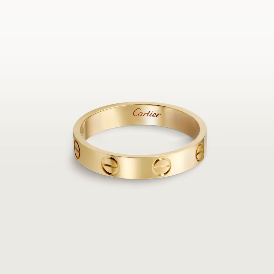 Gold Cartier ring on a light beige background