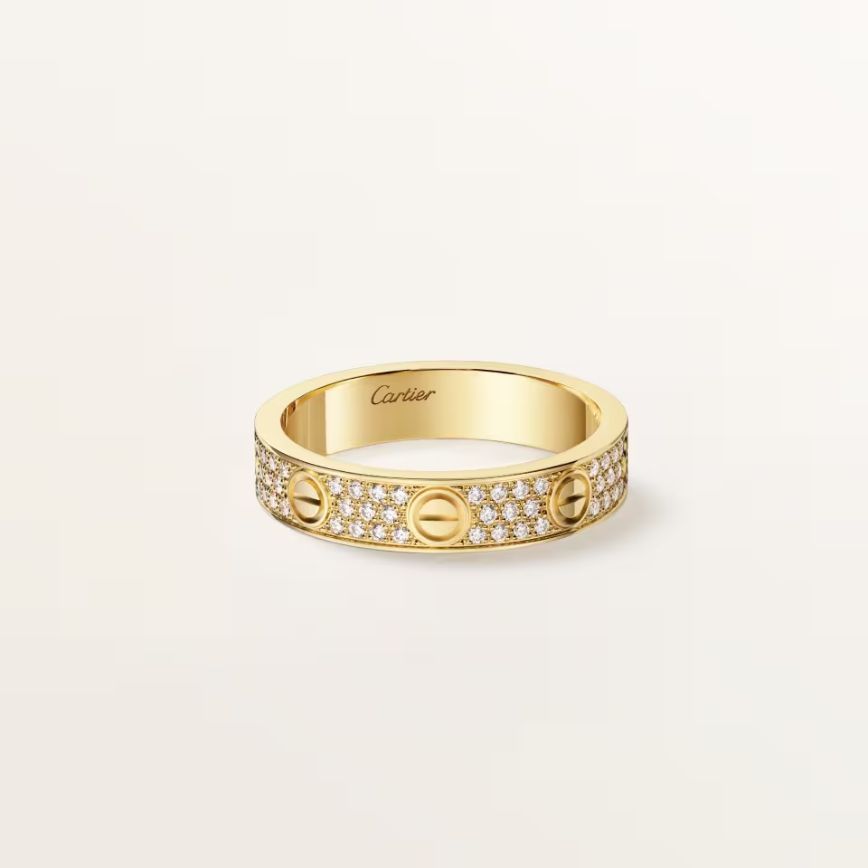 Gold ring with Cartier logo on a light beige background