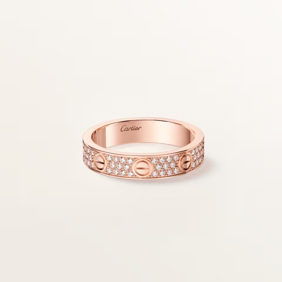 Rose gold ring with diamond accents on a light pink background