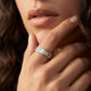 Close-up of a hand wearing a silver ring with intricate design, touching the chin.