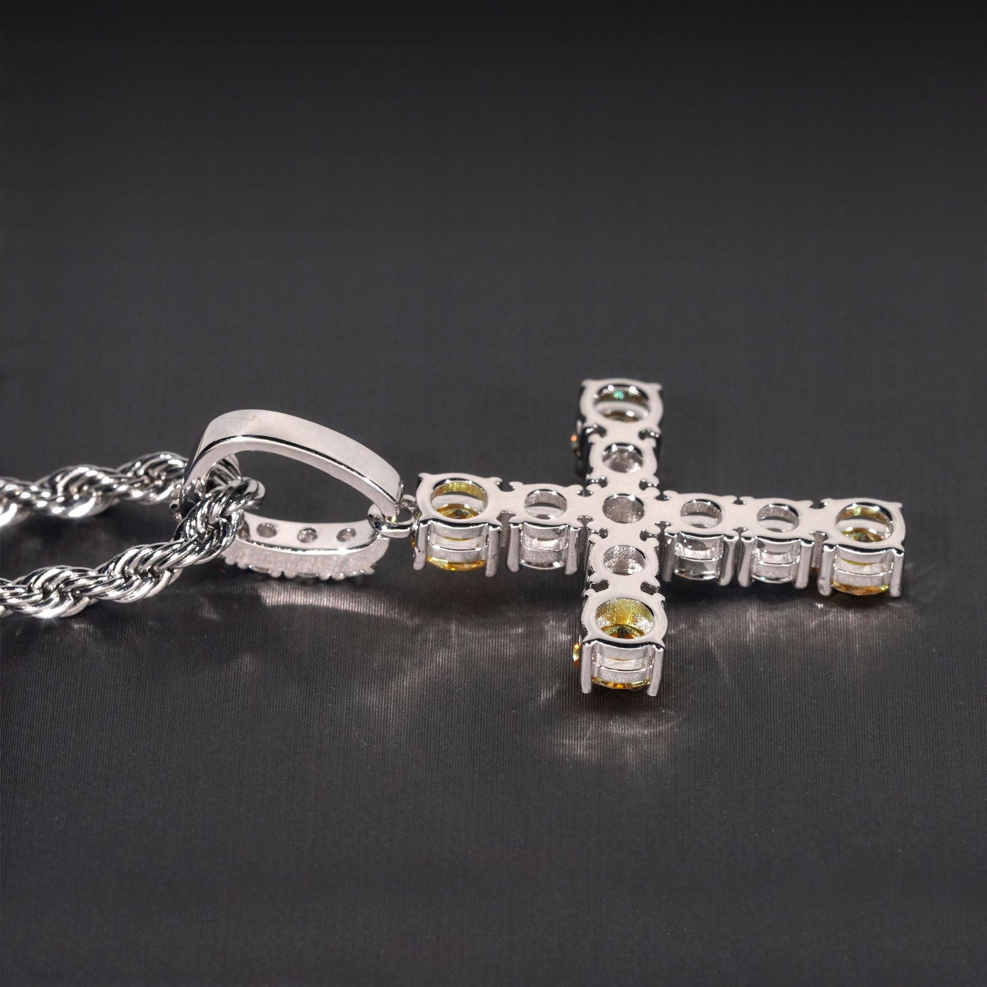Silver cross pendant with embedded stones on a dark background