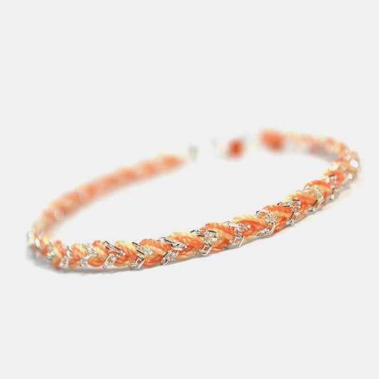 Bracelet with orange and silver braided design on a white background