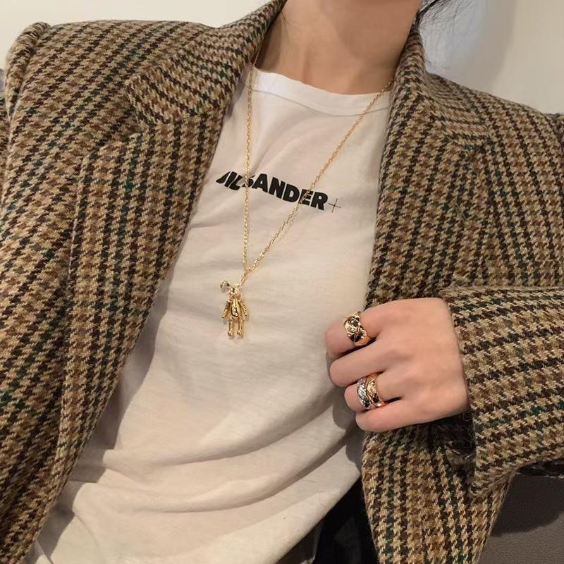 Person wearing a patterned coat over a white shirt with 'Alexander' branding, holding a phone.