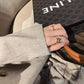Hand holding a handbag with a visible brand logo, wearingChanel_COCO_CRUSH_RING