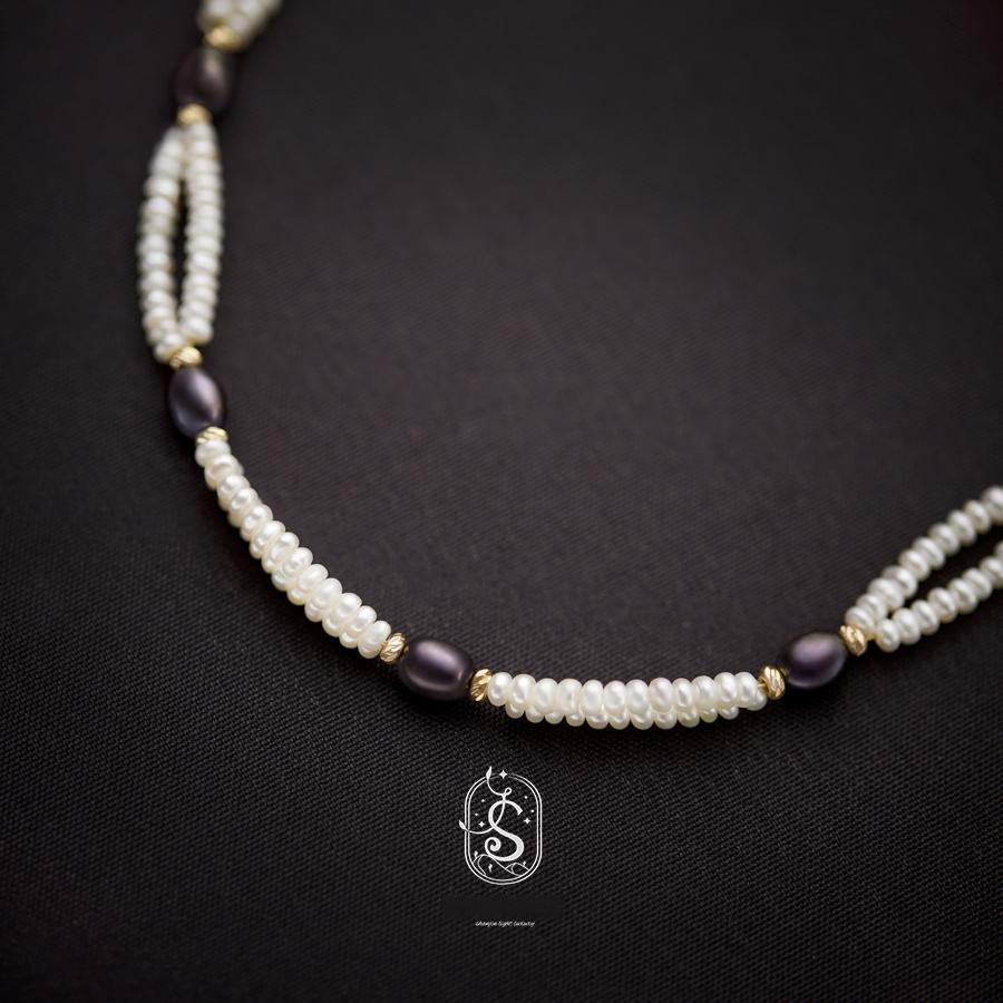 Pearl and purple bead necklace on a dark background