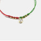 Necklace with red and green cord and gold accents on a white background