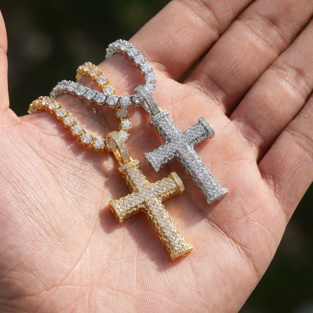 Two cross-shaped pendants on a chain held in a hand.