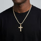 Gold cross necklace with chain on a black shirt against a gray background