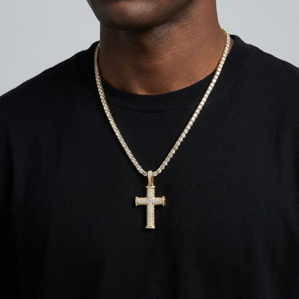 Gold cross necklace with chain on a black shirt against a gray background