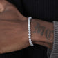 Silver bracelet on a wrist with tattoos, against a dark background