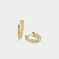 A pair of gold huggie hoop earrings with a row of small clear pavé stones along the front, displayed on a clean light gray background.