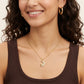 A close-up lifestyle shot of a woman wearing a delicate gold crescent moon necklace with a small cat pendant, styled with gold hoop earrings and a brown ribbed tank top.
