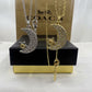 Two Coach New York crescent moon and star necklaces displayed in front of their branded packaging. One necklace is silver with clear rhinestones and a gold star center, and the other is gold with clear rhinestones and a gold star center.