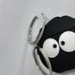 Black airpod case with googly eyes and silver hoop earrings on a white background