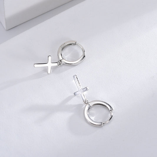 Silver hoop earrings with cross designs on a light gray background