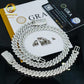 Silver chain necklace with diamond-like stones on a black background with branding visible.