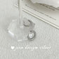 Silver hoop earrings on a clear stand with a soft background