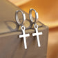 Silver hoop earrings with cross pendants on a textured surface
