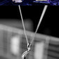 Silver crescent moon necklace with a blurred background of musical instruments.
