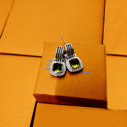 Silver earrings with green gemstones on an orange box