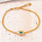 Gold bracelet with a blue gemstone on a textured beige surface