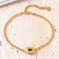 Gold bracelet with a green gemstone on a textured beige surface