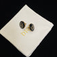 Dior Black CD Signature Stud Costume Jewelry Earringson a white cushion with 'Dior' branding.