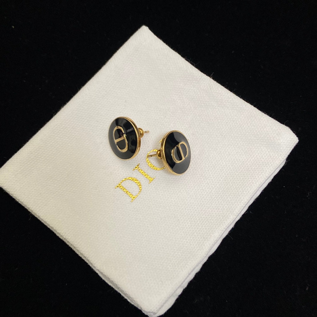 Dior Black CD Signature Stud Costume Jewelry Earringson a white cushion with 'Dior' branding.