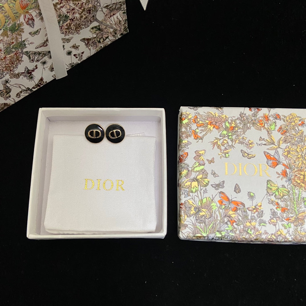 Dior Black CD Signature Stud Costume Jewelry Earringsin a box with a floral-patterned box on a black background