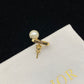 Pearl earring with gold band and 'Dior' logo on a Dior branded cloth background