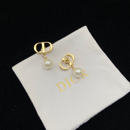 Gold earrings with pearls on a Dior branded pillow