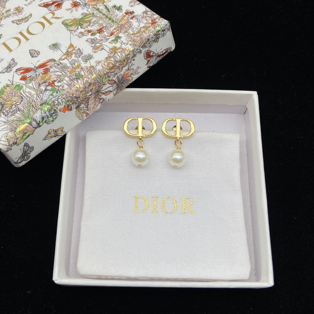 Gold and pearl earrings in a Dior box on a black background