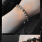 Bracelet with dark beads on a wrist against a dark background