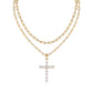 Clean white background — the emerald cut moissanite cross pendant layered with a delicate solo chain on a bust form. The cross catches light, showing the distinctive step-cut facets and brilliant sparkle. Chains drape gracefully without tangling.
