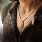 Close-up of a person wearing a necklace with a pendant, focusing on the jewelry.