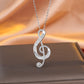 Silver treble clef necklace on a brown surface with a soft orange background