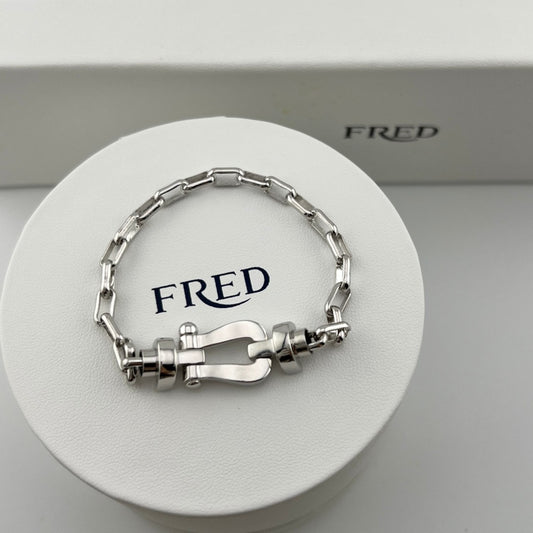 Silver bracelet on a white circular stand with 'FRED' branding.