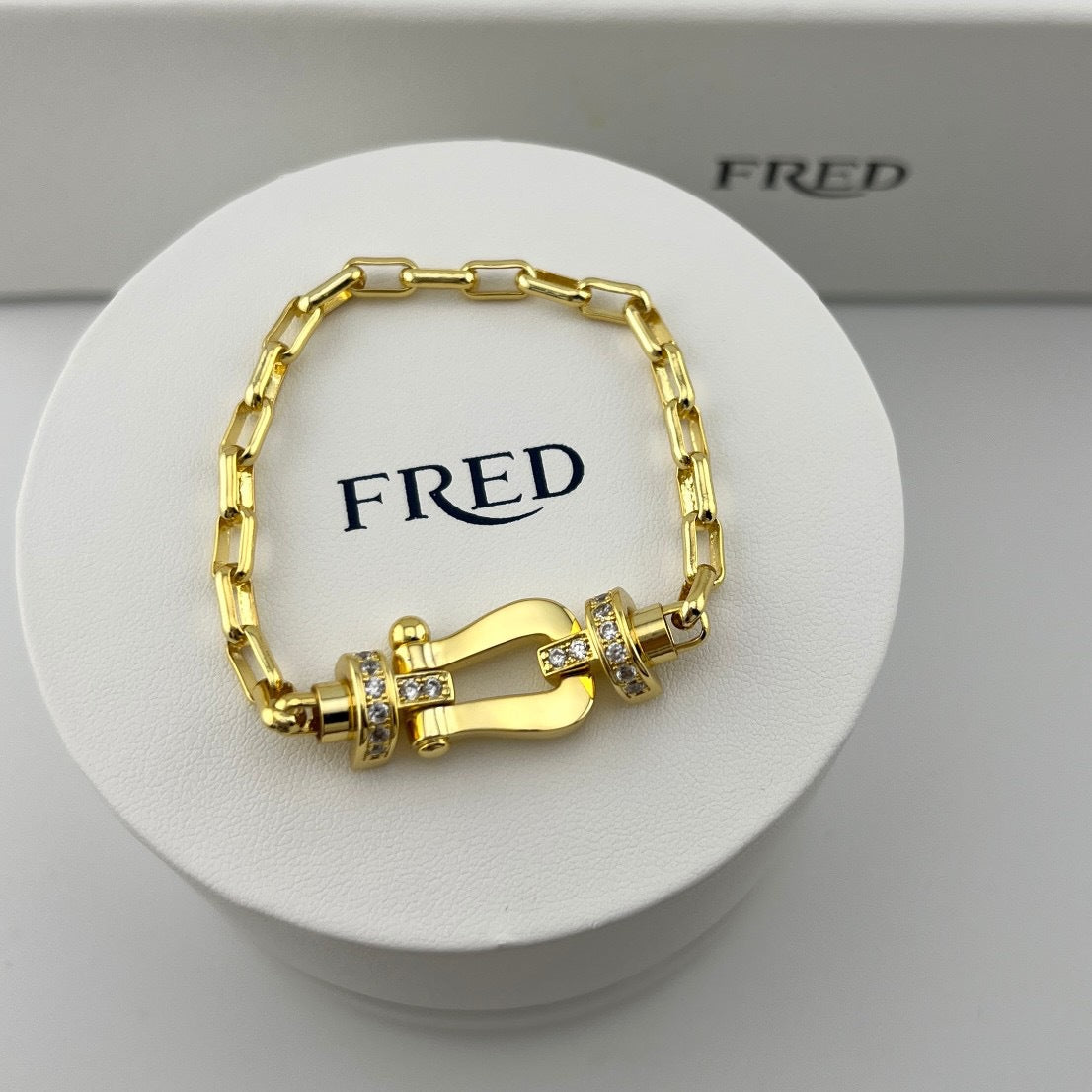 Gold bracelet on a white stand with 'FRED' branding
