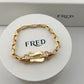 Gold bracelet with diamond accents on a FRED branded stand