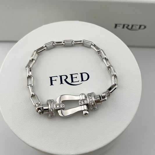 Silver bracelet with intricate design on a white stand with 'FRED' branding.