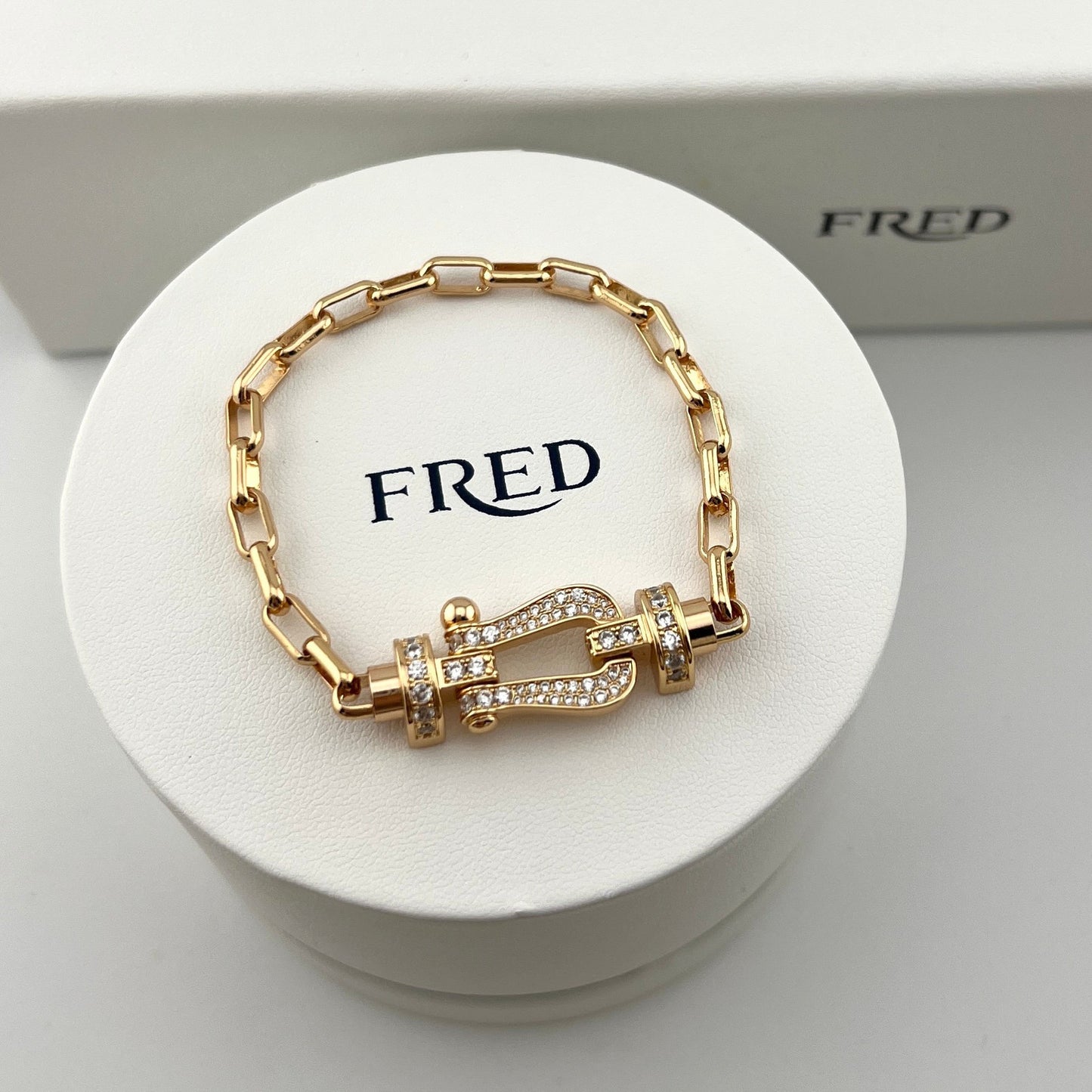 Gold bracelet on a white stand with 'FRED' branding