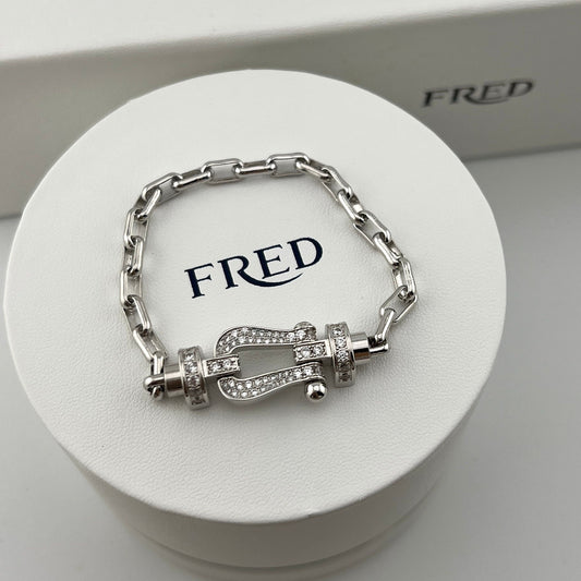 Silver bracelet with intricate design on a white FRED branded stand