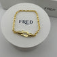 Gold bracelet on a white display with 'FRED' branding