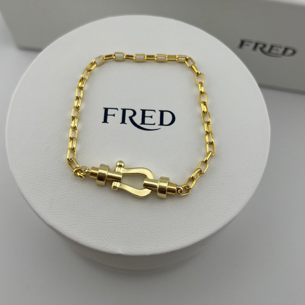 Gold bracelet on a white display with 'FRED' branding