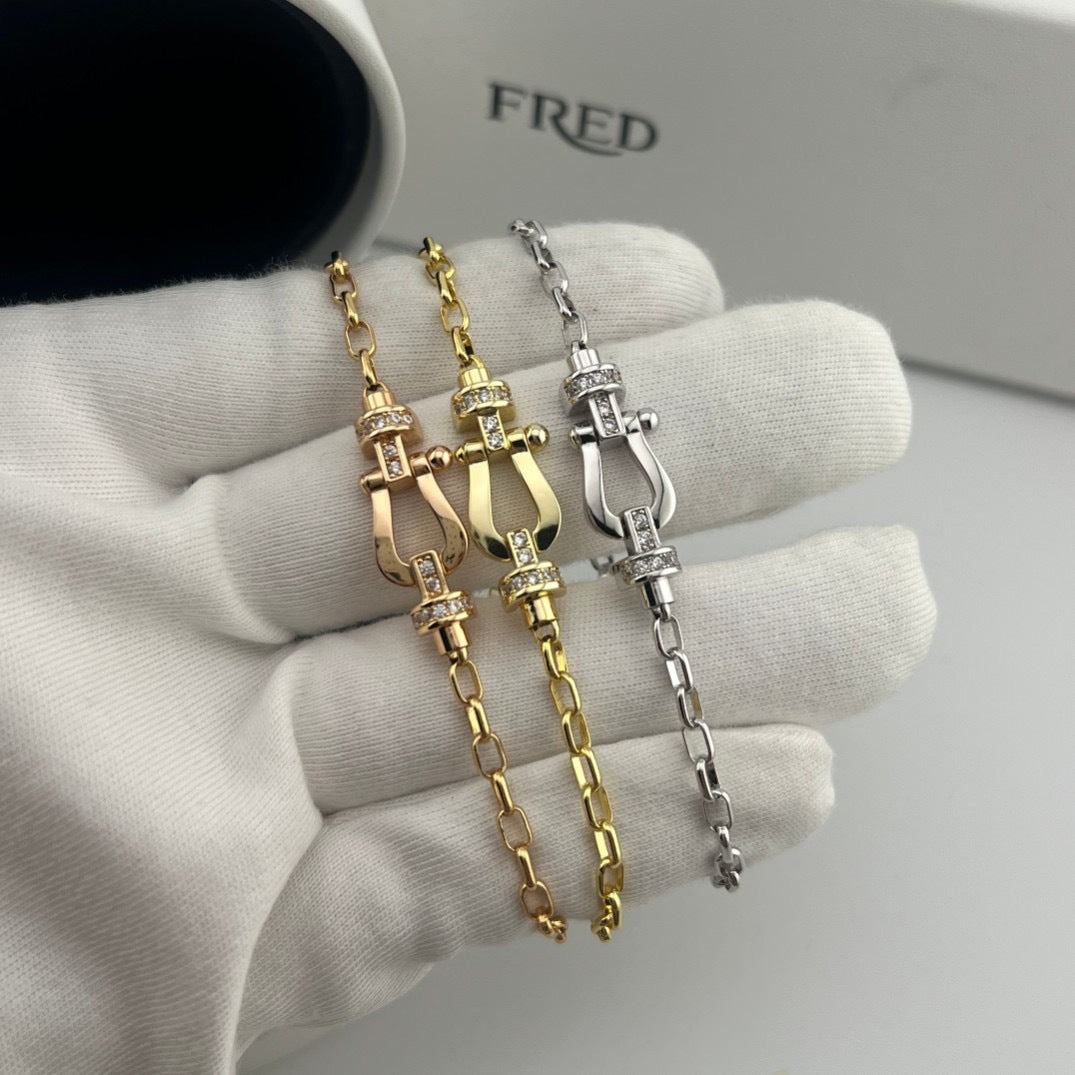 Two gold and silver bracelets on a white surface with 'FRED' branding in the background.