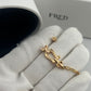 Gold bracelet and earring set on a white glove with 'FRED' branding in the background.